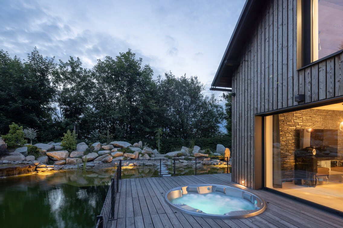 Kruhová vířivka USSPA Orion iN pro 6 lidí zabudovaná ve venkovní zahradě s jezírkem