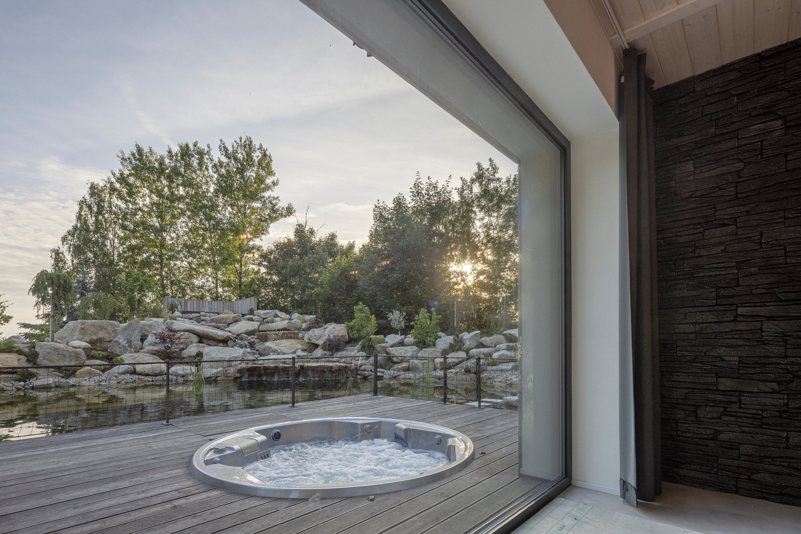 Kruhová vířivka USSPA Orion iN pro 6 lidí zabudovaná ve venkovní zahradě s jezírkem