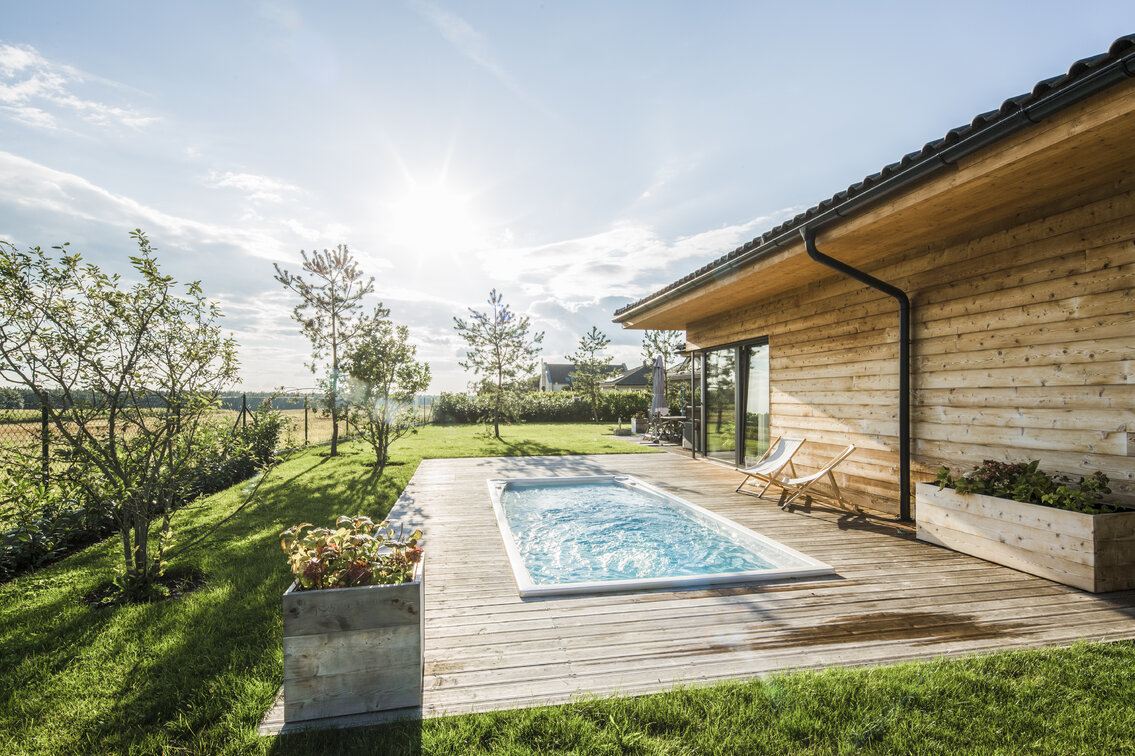 Swim Spa XL od USSPA integrovaná do dřevěné terasy, obklopená zelení